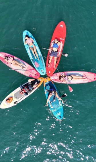 A group of people on paddleboards arranged in a circular formation on turquoise water. 2