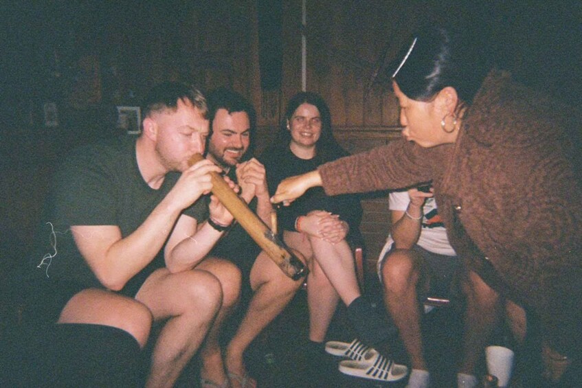 A group of people sitting closely together, some holding objects. 1
