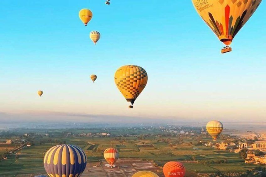 Hot air balloons over a rural landscape with fields and a few buildings. 1