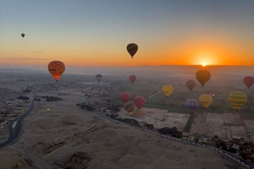 A landscape with multiple hot air balloons at sunset. 3