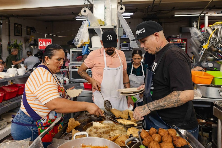 A busy food stall with people cooking and serving food. 3