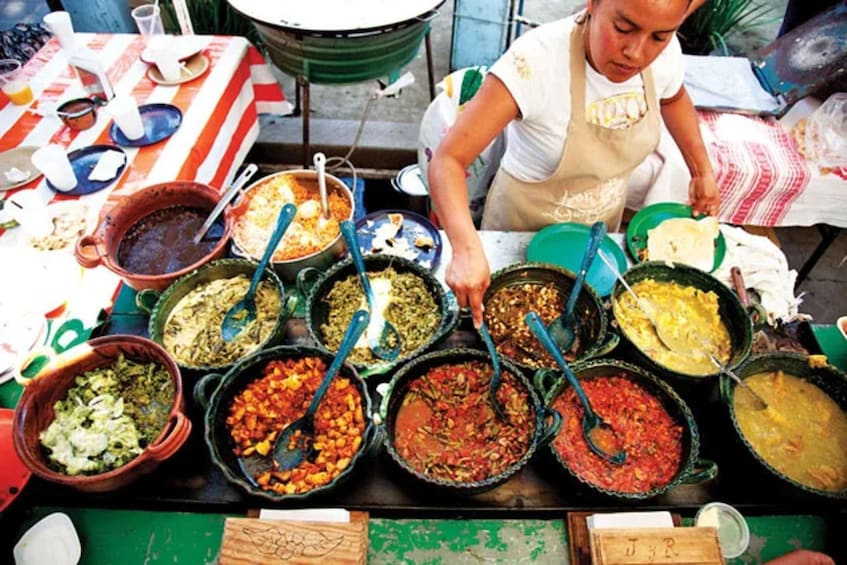 A street food vendor preparing various dishes in large pots. 2
