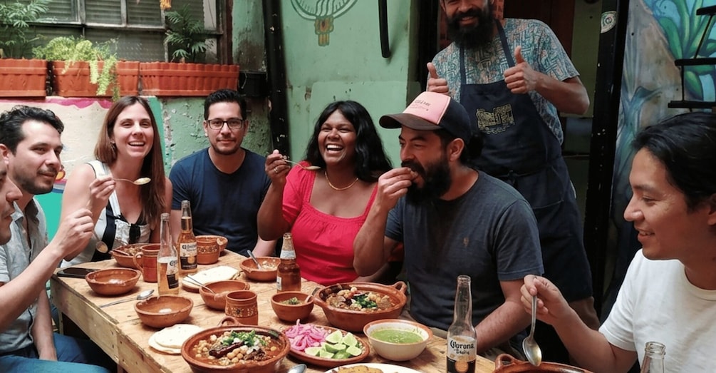 A group of people dining outdoors with various dishes and drinks on a table. 1
