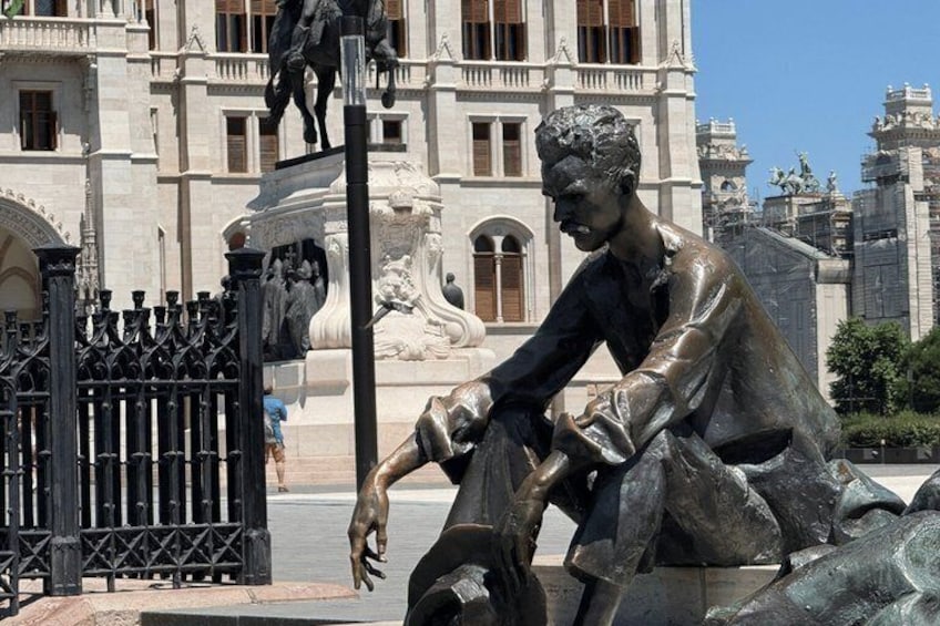 A statue of a seated man with a horse, a fountain, and a building in the background. 5