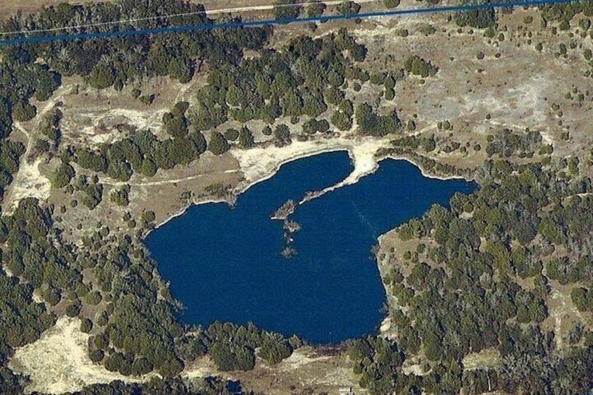 A large body of water surrounded by dense forest and open land. 4