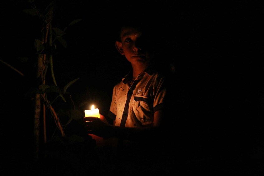 A person holding a lit candle in a dark environment. 3