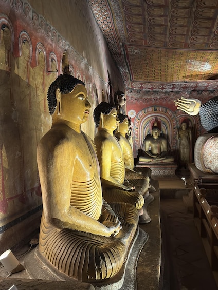Large golden Buddha statues in a temple with intricate wall paintings and a patterned ceiling. 3