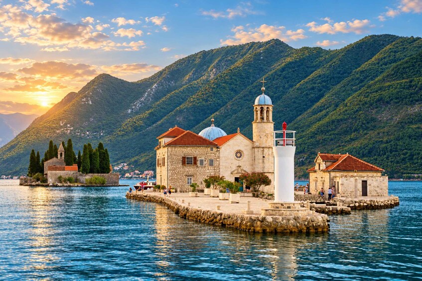 A coastal town with a prominent church and lighthouse on a small island, surrounded by mountains and a clear sky. 4
