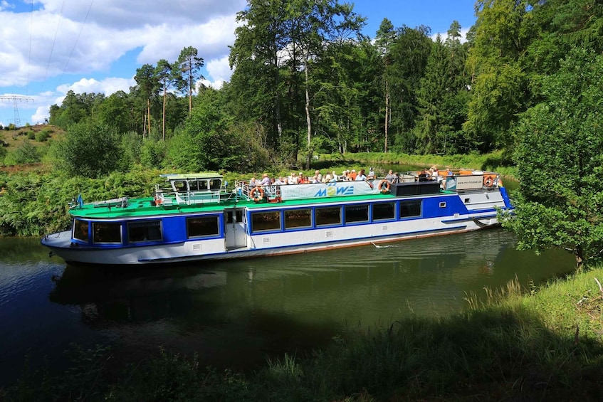 A riverboat with passengers, surrounded by dense forest and a clear sky. 1