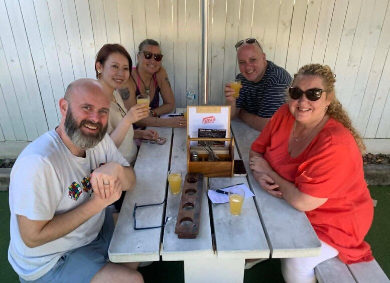 A group of people sitting at an outdoor table with drinks and a menu. 5
