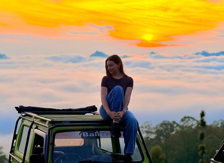 A person sitting on the roof of a vehicle with a sunset in the background. 3