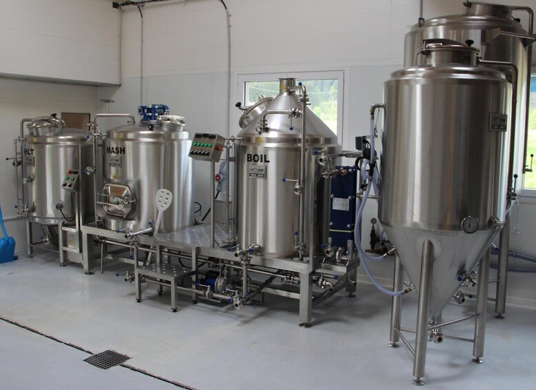Stainless steel brewing equipment, including tanks and a control panel, in a clean industrial setting. 1