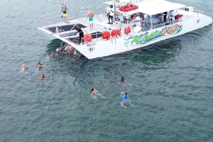 A boat with people swimming in the water around it. 1