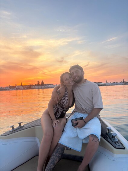 A couple on a boat during sunset with a cityscape in the background. 3