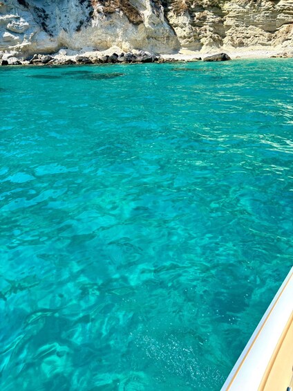 Clear turquoise water, rocky cliffs, and a boat. 4