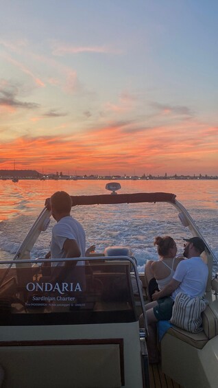 A boat with three people on board, a sunset in the background, and the name 'ONDARIA Sardinian Charter' on the side. 2