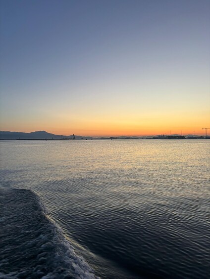 A calm body of water reflecting the sky during sunset with distant landforms. 3
