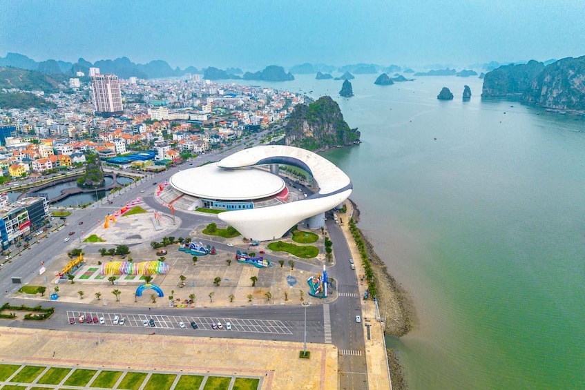 A modern stadium with a unique curved roof, surrounded by a parking lot and a river. 4