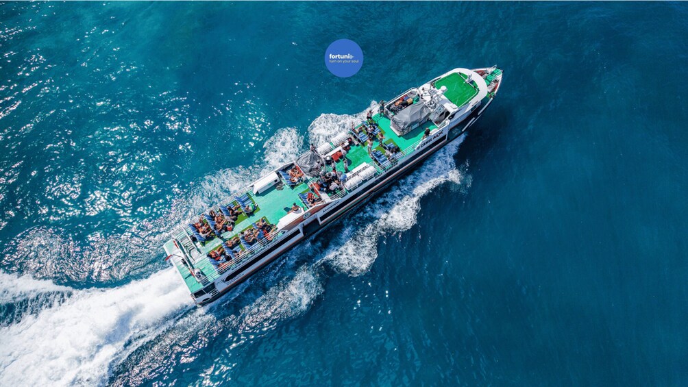 A large cruise ship with a green deck and a logo 'fortuni' in the sky. 1