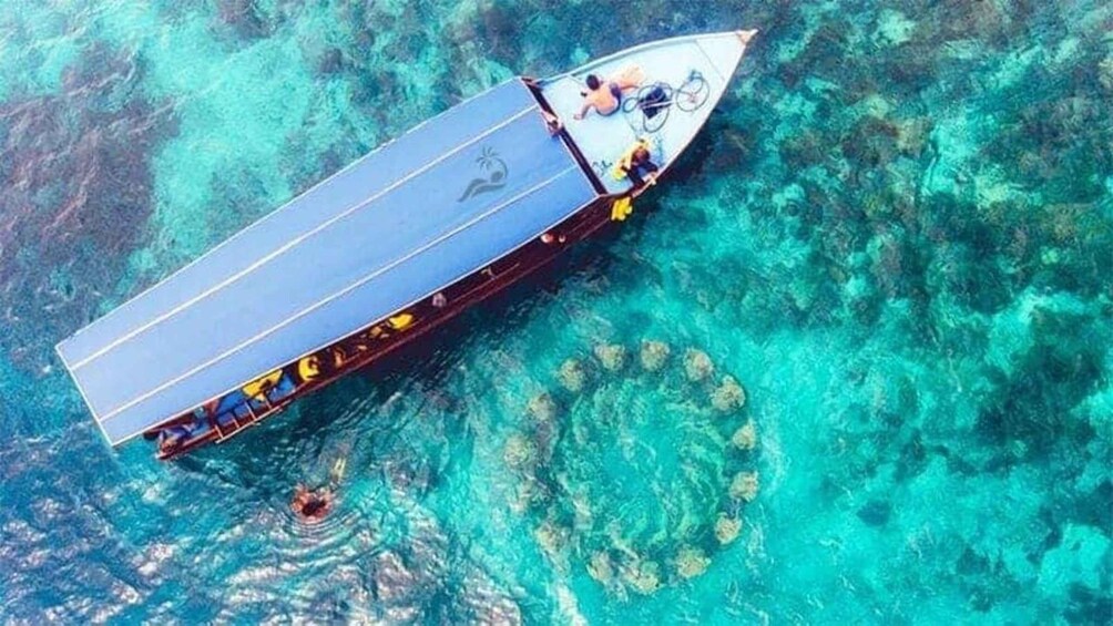 A boat with a blue roof and yellow seats, floating on clear turquoise water with coral formations. 4