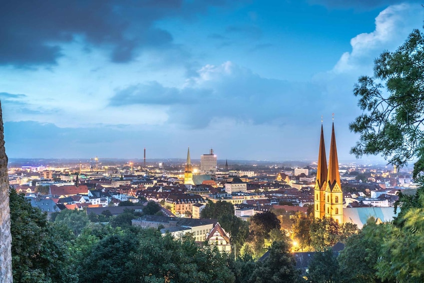 A cityscape at dusk with prominent church spires and illuminated buildings. 2