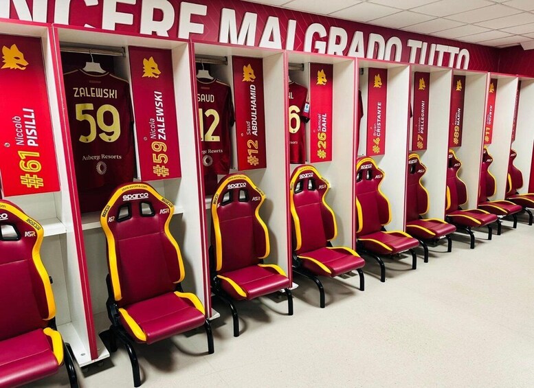 A row of red and yellow team benches with jerseys hanging above. 4