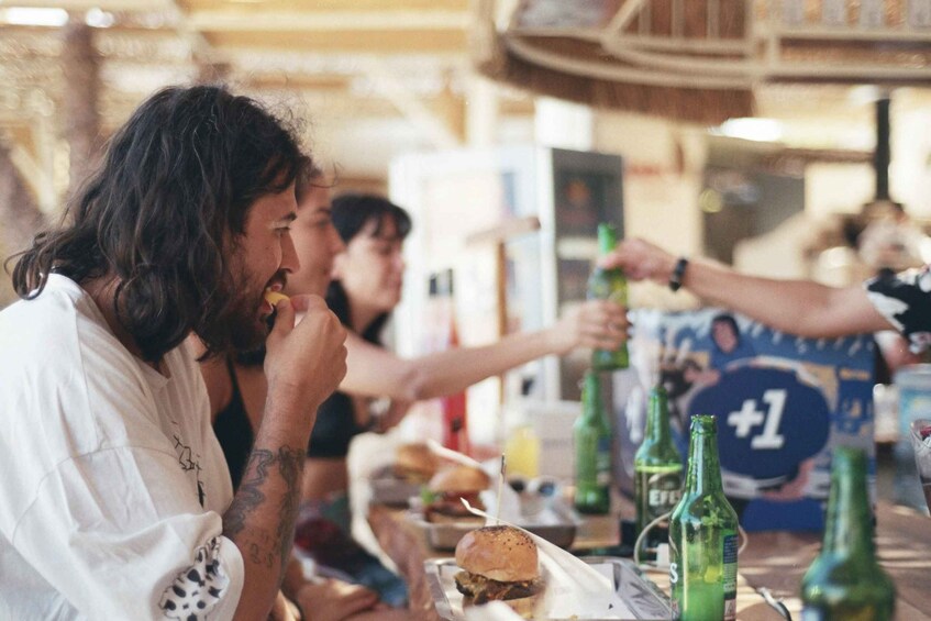 People sitting at a table with burgers and green bottles. 5