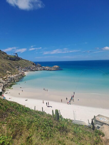 A coastal beach with clear turquoise waters, sandy shores, and sparse vegetation. 4