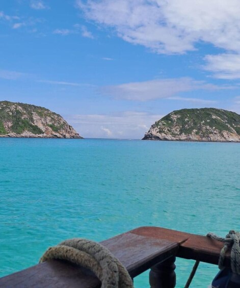 A boat with a view of turquoise sea and two green hills in the distance. 1