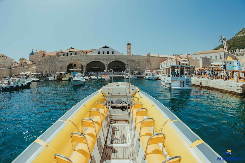 A boat with yellow seats in a harbor with historic buildings and a tower. 3