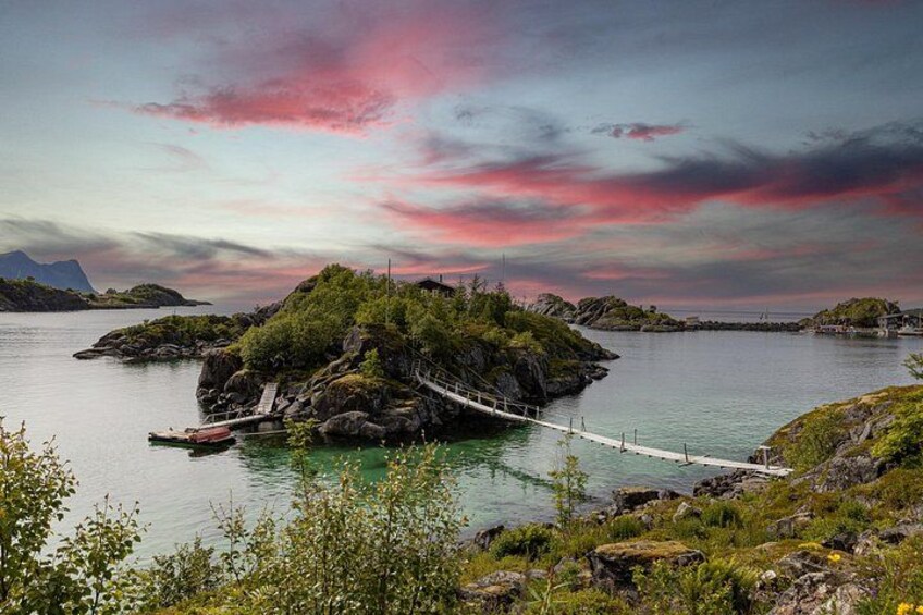 A rope bridge over calm water, surrounded by lush greenery and rocky terrain. 3