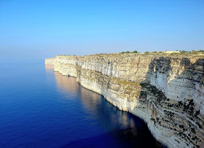 A coastal cliff with layered rock formations and a calm sea. 4