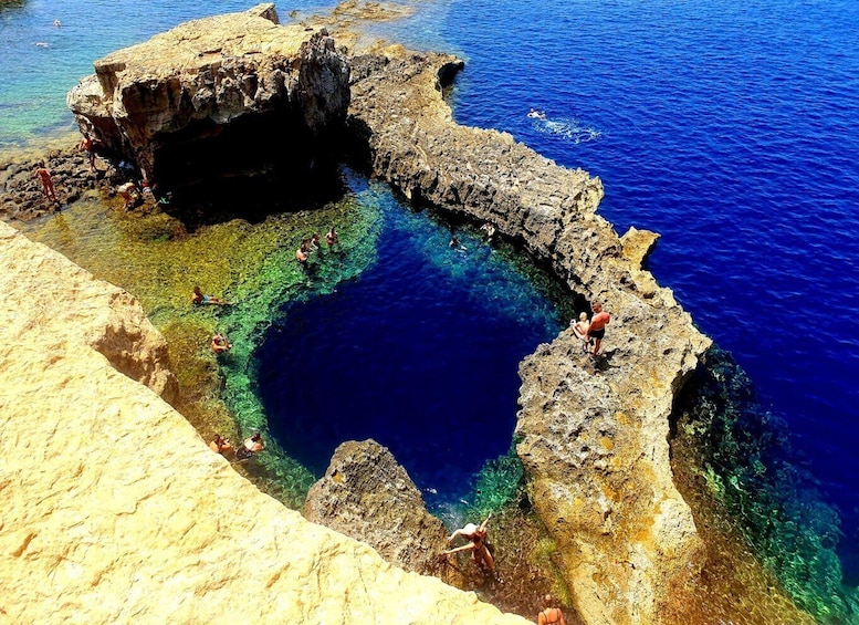 A natural pool surrounded by rocky cliffs with clear blue water. 3