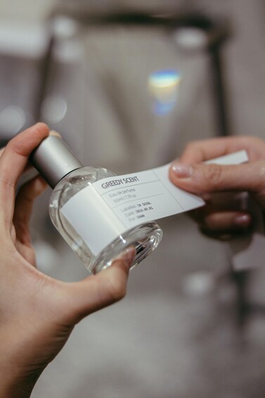 A person holding a perfume bottle with a label. 4