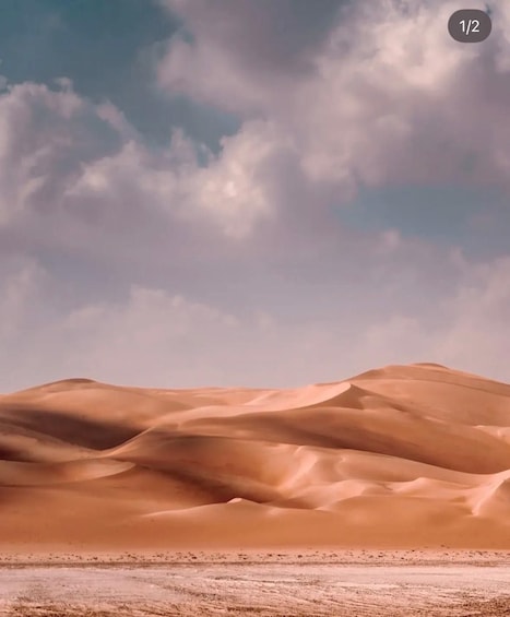A desert landscape with sand dunes under a partly cloudy sky. 3