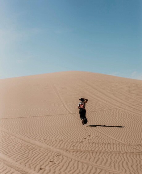 A person standing on a sand dune with a clear sky above. 4
