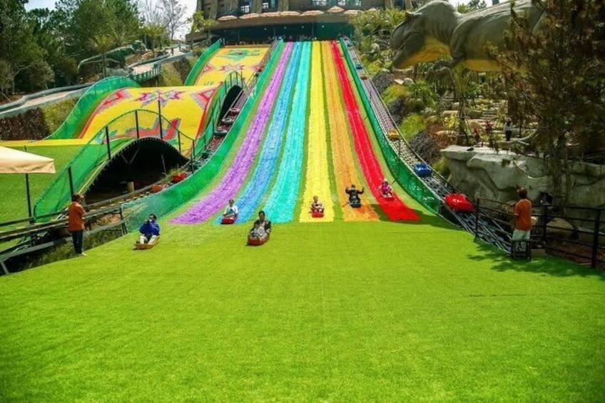 A multi-colored water slide with people sliding down. 1