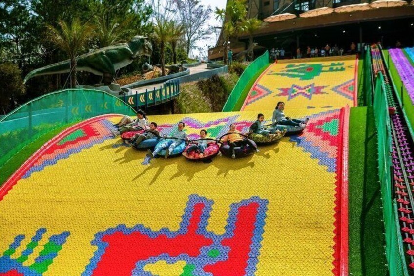 A colorful slide with people at the top, a green netted area, and a patterned ground. 3