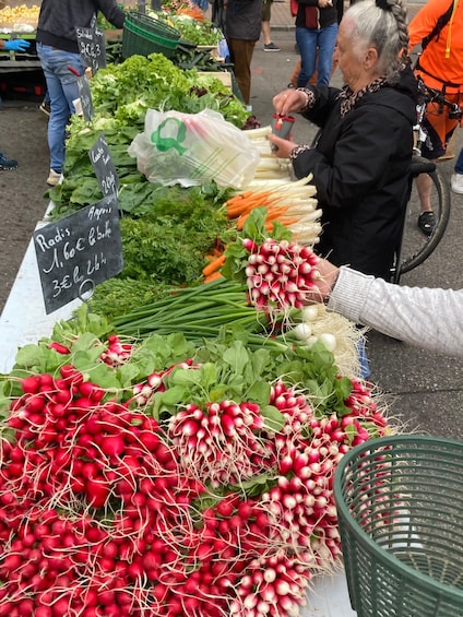 A vegetable stand with radishes, carrots, and leafy greens. 4