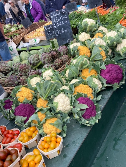 A variety of vegetables at a market stall, including cauliflower, broccoli, and artichokes. 3