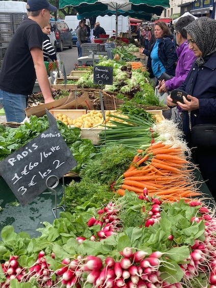 A vegetable market with radishes, carrots, and other greens on display. 2