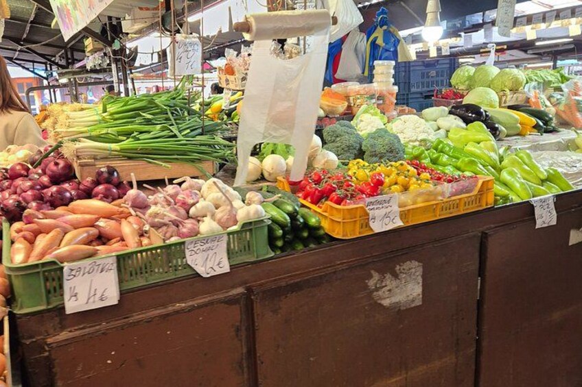 Een kraam op een markt met diverse groenten, zoals broccoli, bloemkool en paprika. 2