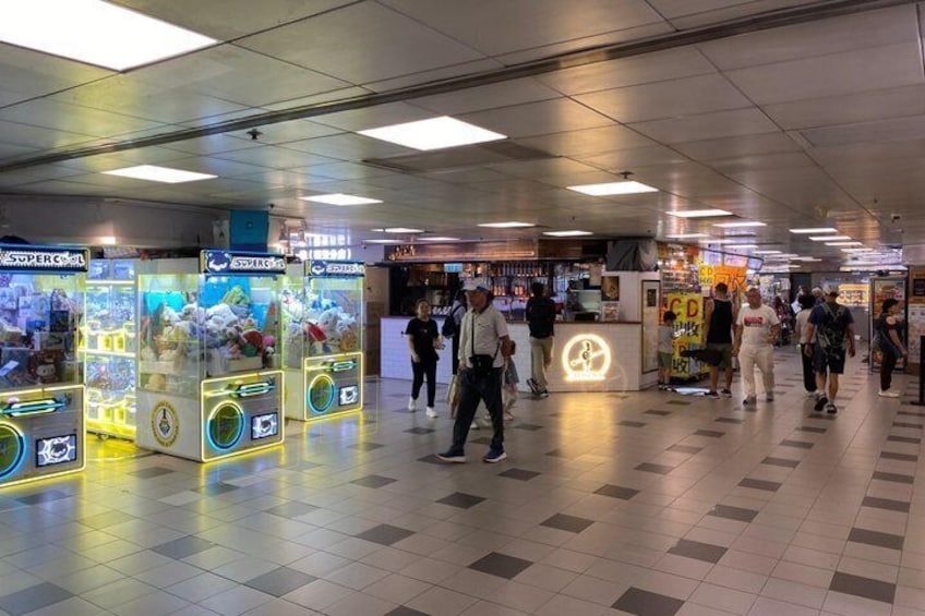A subway station with arcade machines and people walking. 4