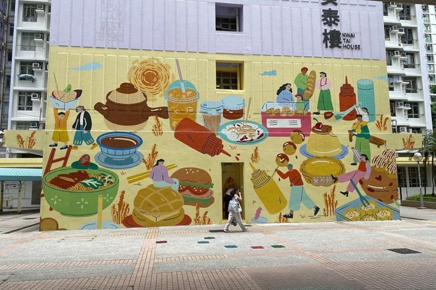 A colorful mural on a building depicting various food items and people. 3