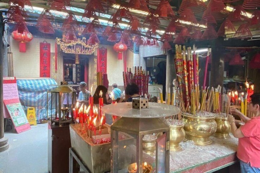 A temple interior with incense burners, red lanterns, and a chandelier. 2