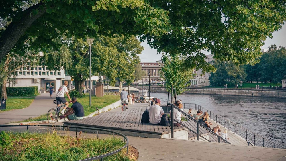 A riverside walkway with people walking, sitting, and cycling. 4