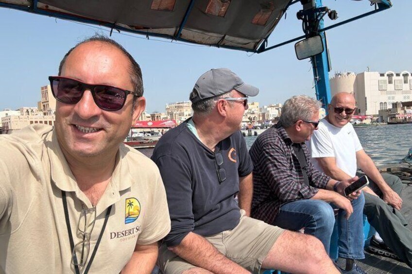 Eine Gruppe von Menschen auf einem Boot, im Hintergrund eine Stadtansicht. 5