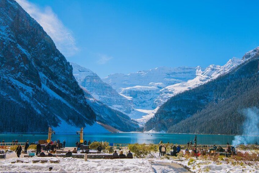 A snowy mountain landscape with a lake, a train, and a group of people. 2