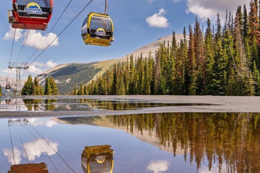 Un lago que refleja telecabinas y una montaña boscosa al fondo. 1