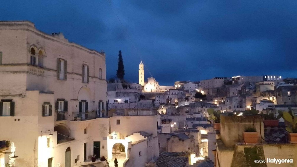 Un pueblo histórico al anochecer con edificios iluminados y una torre destacada. 4
